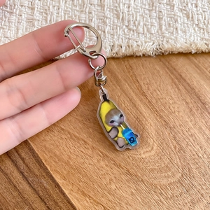 Detailed view of banana cat acrylic keychain with blue drink cup held in hand