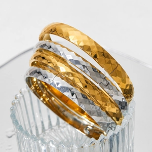 Gold and silver stainless steel bangles with elegant diamond-cut texture on white background