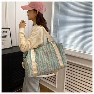 Detail of green travel bag with beige letter prints and wide adjustable shoulder strap