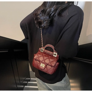 Detail of burgundy quilted leather mini bag with gold twist lock and chain strap