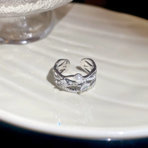 Detail view of adjustable silver ring with pearl and teardrop zircon on white plate