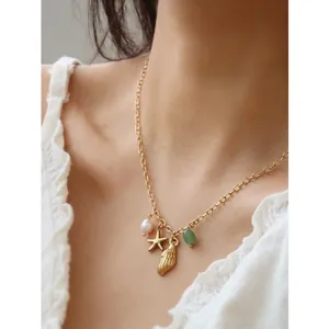 Gold ocean theme necklace with starfish shell pearl and green gemstone on female neck