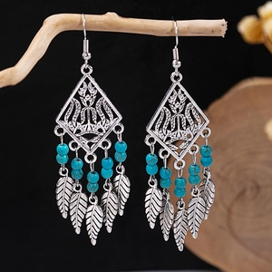 Detailed macro view of Bohemian silver tassel earrings with turquoise beads and leaf charms