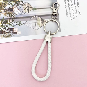 Close-up of white braided leather keychain with polished silver metal ring and clasp