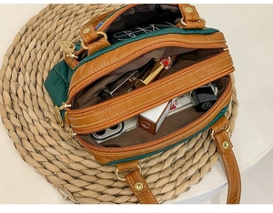 Overhead detail view of green textured leather bag with dual zipper compartments