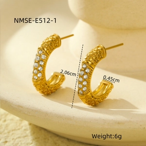 Close-up of golden C-shaped hoop earrings with scale texture and micro-set cubic zirconia
