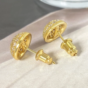 Macro shot of gold dome stud earrings with paved cubic zirconia and secure push backs