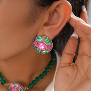 Gros plan sur des boucles d'oreilles rondes avec cristaux roses et touches d'émeraude