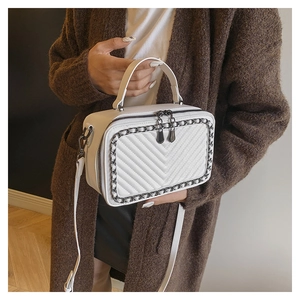 Dettaglio borsa a tracolla bianca con trapuntatura a V e catena decorativa elegante