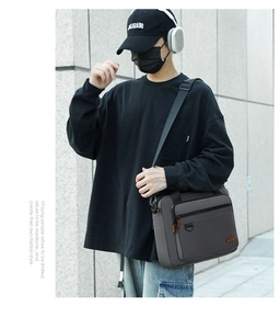 Close-up of a dark grey men's business crossbody bag featuring multi-layer zippers and D-buckle