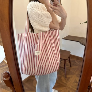 Detail of red and white striped canvas tote bag with front pocket for daily commute