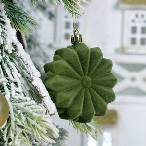 Green flocked star Christmas ornament hanging on a cedar branch with golden string