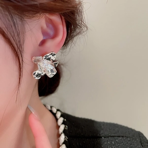 Close-up of model wearing irregular silver flower stud earring with hammered metal texture