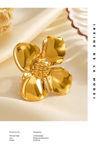 Macro detail of chunky 18K gold-plated stainless steel flower ring on white silk fabric