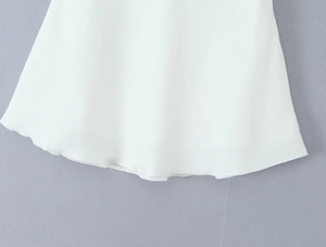 Détail de l'ourlet ondulé d'une jupe mi-longue en satin jacquard blanc pour femme