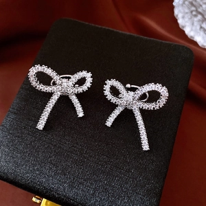Close-up of sparkling bow earrings with micro-pave zircons on a luxury black jewelry box
