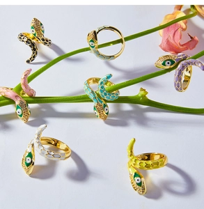 Detail of colorful enamel snake rings with zircons on a green decorative branch