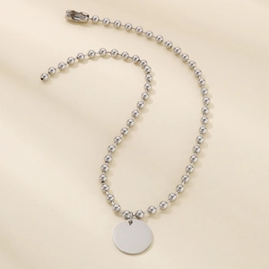 Gros plan d'un collier en chaîne à billes argentées avec un pendentif disque rond poli