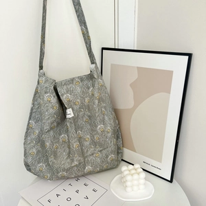 Detailed view of gray tote bag with peacock feather pattern on a white table
