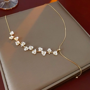 Close-up of gold plated necklace featuring white flowers and pearls on jewelry box