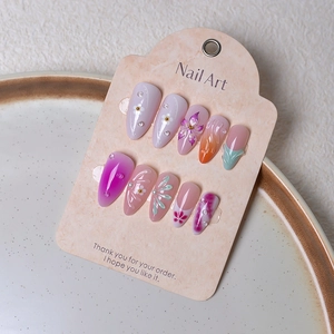 Close-up of almond press-on nails with 3D floral designs and pearl accents on tray
