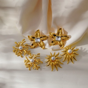 Detail of golden floral earrings with pearls and crystals on beige silk fabric