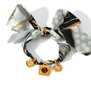 Detail showing silk ribbon hair tie with heart, tiger eye stone, and sun face metal charms