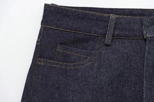Macro view of dark blue denim shorts with contrast orange stitching and waist detail
