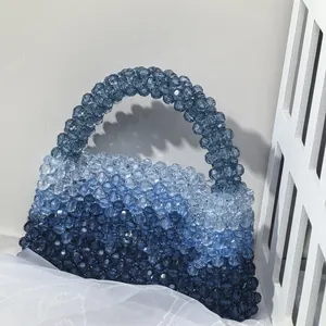 Detailed close-up of handmade beaded handbag with blue gradient beads and woven handle