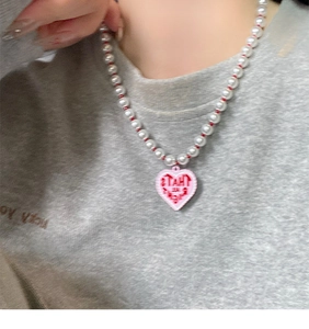 Close-up of heart-shaped pink pendant necklace with white imitation pearls on model