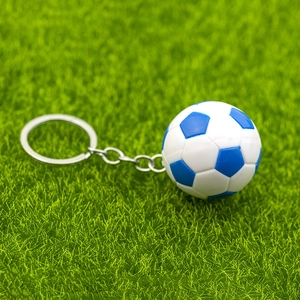 Gros plan du porte-clés mini ballon de football bleu et blanc sur gazon vert