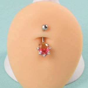 Detailed close-up of a silver navel ring with a gradient orange gemstone on a model