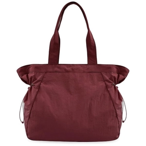 Detalle del bolso tote de nailon marrón rojizo con cierre de cordón y textura suave