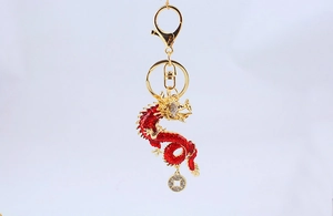 Macro shot of golden dragon keychain with red enamel scales and rhinestone coin charm