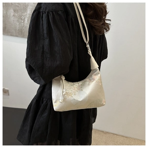 Detail of embroidered beige silk bucket bag showing floral patterns and shoulder strap size