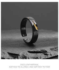 Close-up of black and gold ring with irregular textures on a dark stone surface