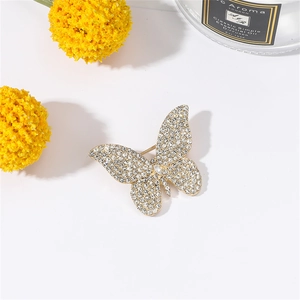 Detailed macro view of a gold-toned butterfly brooch encrusted with sparkling rhinestones