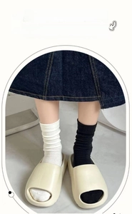 Close-up of ribbed cotton knee-high socks styled with platform slide sandals