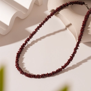 Detailed close-up of vintage dark red beaded necklace on white geometric display stand