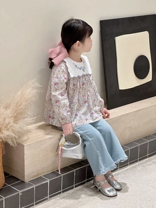 Detail of a floral long-sleeve blouse and light blue denim wide-leg pants set for girls