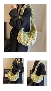 Detail view of large grass green quilted cloud bag worn by a model in casual style