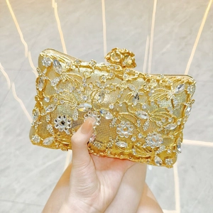 Close-up of gold evening clutch with delicate floral lace and shimmering rhinestones