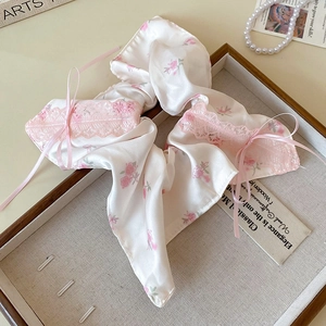 Détail d'un chouchou floral avec bordure en dentelle rose et nœud sur plateau bois