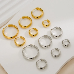 Various sizes of gold and silver hoop earrings displayed on a textured white stone surface