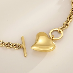 Detalle de un colgante de corazón de oro pulido con un cierre de barra en T en el collar