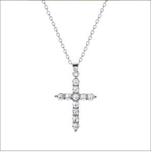 Close-up of a silver cross necklace pendant set with shimmering round crystals on a fine chain