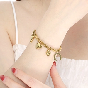 Detail of 18K gold plated charm bracelet featuring heart, elephant and clover pendants