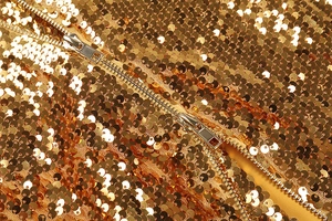 Détail de paillettes dorées avec fermeture éclair métallique sur une robe de soirée chic