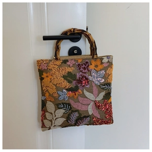 Detailed view of linen handbag with bamboo handle and floral embroidery sequins