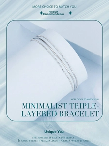 Detailed view of silver triple-layered snake and bead chain bracelet on a white display